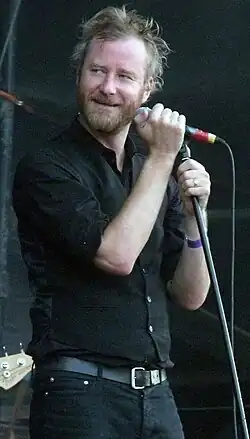 Matt Berninger, dressed in black, staring to his right while holding a mic