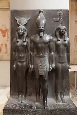 Statue of Menkaure with Hathor and Cynopolis; 2551–2523&nbsp;BC; schist; height: 95.5&nbsp;cm; Egyptian Museum (Cairo). Demonstrates a group statue with Old Kingdom features and proportions.[23]