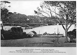 Postcard of Milsons Point. The caption reads: "Milson’s Point – Probably in the early Seventies [1870s]. Kirribilli on the farther shore. Eastern Road Wharf is front. Alfred St to the right, the Arcade and clock are within (illegible)ing distance of the spreading tree."