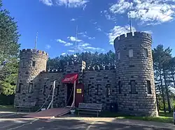 Exterior of stone Castle-like building. One story with two towers on either end.