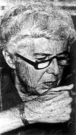Portrait of an older woman wearing glasses with her chin resting on her right fist