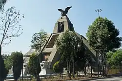 The Monumento a la Raza is a stone structure inspired by Mesoamerican pyramids. At the top, a statue of an eagle with its wings spread is featured, while the next level showcases a statue of a standing man.