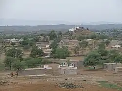 The brick dwellings of the village nestled among hills and low mountains with a white mosque situated on a hilltop