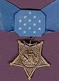 A light blue neck ribbon with a gold star shaped medallion hanging from it. The ribbon is similar in shape to a bowtie with 13 white stars in the center of the ribbon.