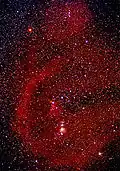 Long exposure of Orion with red clouds of ionized hydrogen (H-alpha). The big bow on the left is Barnard's Loop.
