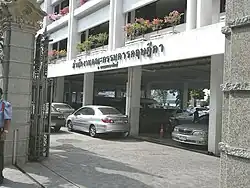A building has a parking level for the ground floor. Office windows have planters with flowers.