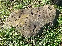 Rock with two grooves and several pecked holes