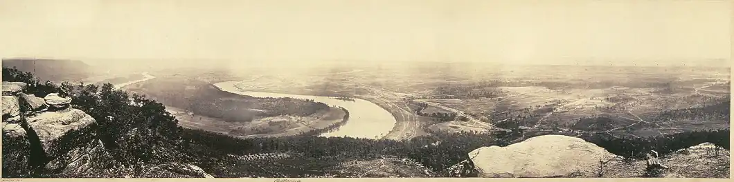 Wide view from high up on the mountain with river bends stretching towards hazy indistinct open land in distance