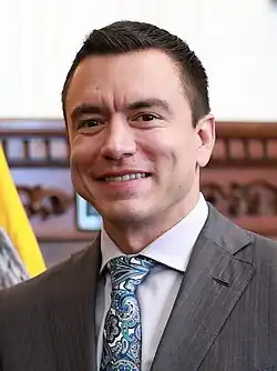 Headshot of Daniel Noboa. He is a clean-shaven, Latino man with very short hair, wearing a suit with a tie.