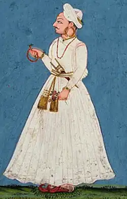 A color portrait of a turbaned man wearing a white dress
