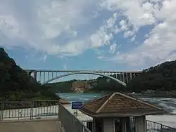 The bridge as viewed from Canada, with collapsed Schoellkopf Power Station visible in the distance