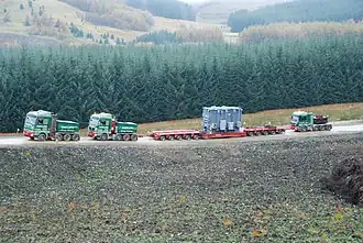 Two MAN SE ballast tractors pulling and one Mercedes pushing a 100,000&nbsp;kg (220,000&nbsp;lb) transformer on 10-axle lowboy