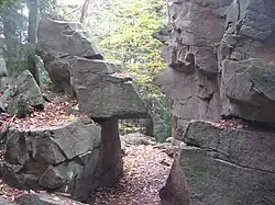 Photo of a path passing through a narrow gap between angular rocks; the two sides of the gap look as if they once fit together.