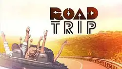 An image of people in a vehicle, with their hands raised, with a road and trees on the background. The show title is displayed on the upper side of the image.