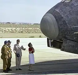 "President Ronald Reagan chats with NASA astronauts Henry Hartsfield and Thomas Mattingly on the runway as first lady Nancy Reagan scans the nose of Space Shuttle Columbia following its Independence Day landing at Edwards Air Force Base on July&nbsp;4, 1982."[18]