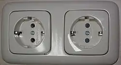 Schuko outlets manufactured by Busch-Jaeger Elektro. The right socket has protective shutters (gray in color) and the left does not.