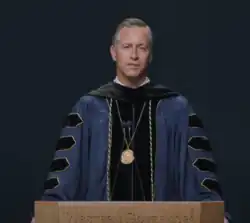 Photo of University President Scott Pulsipher in robe behind lectern.