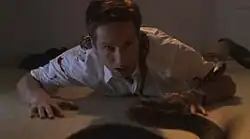 A man lies on the floor, covered in rattlesnakes.