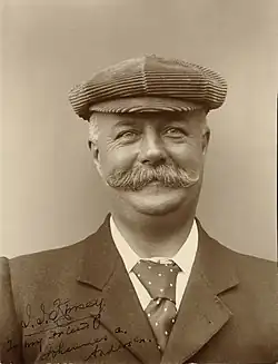 Head and shoulders portrait of a man in his fifties with moustache wearing a hat