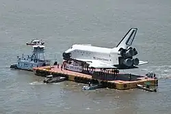Aerial view of Space Shuttle Explorer atop a barge transport
