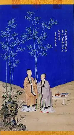 Painted vertical scroll with two men wearing robes standing on a rocky landscape and against a deep-blue sky. A strange-looking stone stands in the left foreground. There are five green bamboos in the background, and a low table with several objects on it is placed on the ground on the right. The man on the left, who is taller and looks older, is giving a long object that might be a tree branch with flowers on it to the man on the right.