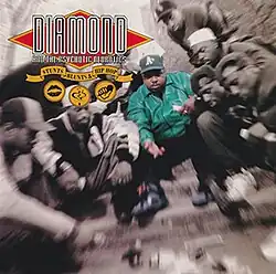 A photo of Diamond D playing dice with a group of men on a street. The photo is mostly monochrome and is slightly blurred. It is focused on Diamond D, who is located in the middle and is the only person colored. In the top left corner there is the "Diamond and the Psychotic Neurotics" logo, a yellow ribbon with the album's title, and three small yellow pictures, showing lips, smoke, and a microphone.
