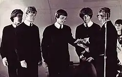 A black-and-white image of four men standing on a stage receiving a prize