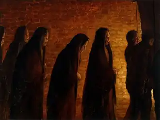 six hooded figures walk rightwards bathed in a dim yellow light from an unseen source