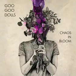 An art piece in beige with a woman holding flowers in front of her face that are purple