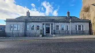 a grey gantite building with two columns at the front door