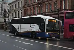 A white, blue and gold coach parked in a city street