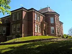 A large red brick house on a grassy mound