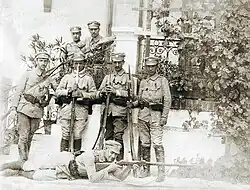 Photograph of a group of men in uniforms posing on a porch. See caption for details.