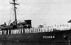 Officers and crew line the rails while in port.