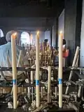 Image of three lit candles in a room full of more candles