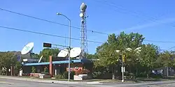 A one-story midcentury building with WFRV-TV signage, satellite dishes on the roof, and a tower with a large radome on top.