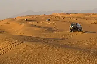 Vehicles on the dunes near the Eastern Hajar Mountains