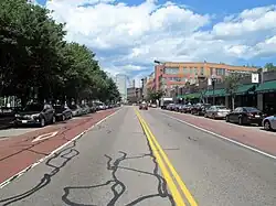 A urban street with parallel parking, a red bus lane, and a genera travel lane in each direction
