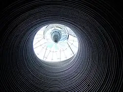 Dark image with light coming from a circular opening at the top of the funnel