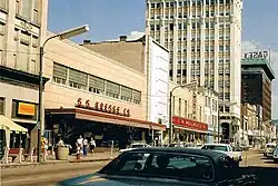 A downtown shopping street. Visible at left-center is a two-story building with modernist design and a sign reading "S. S. Kresge Co."